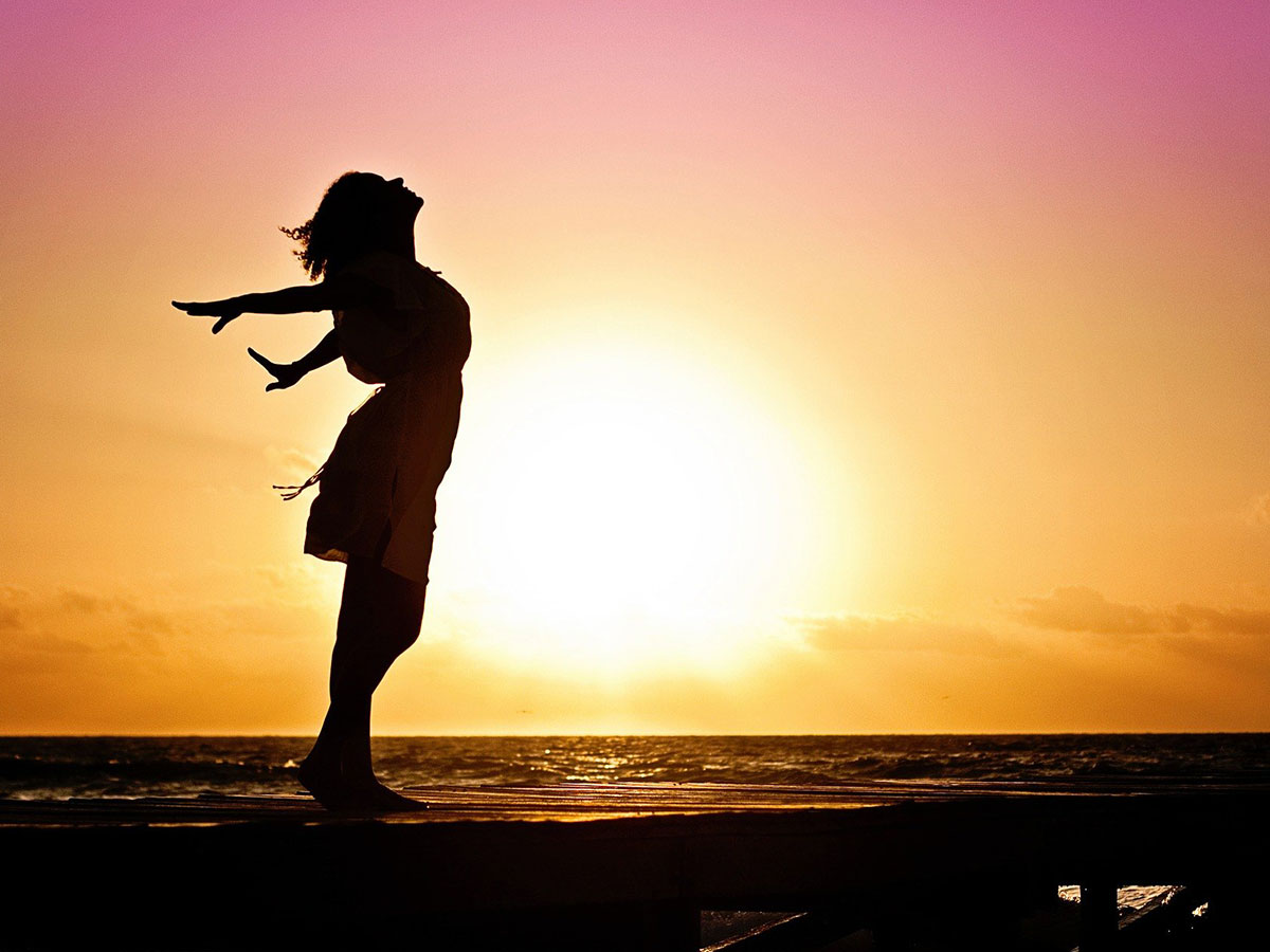 Woman Standing on Beach at Sunset